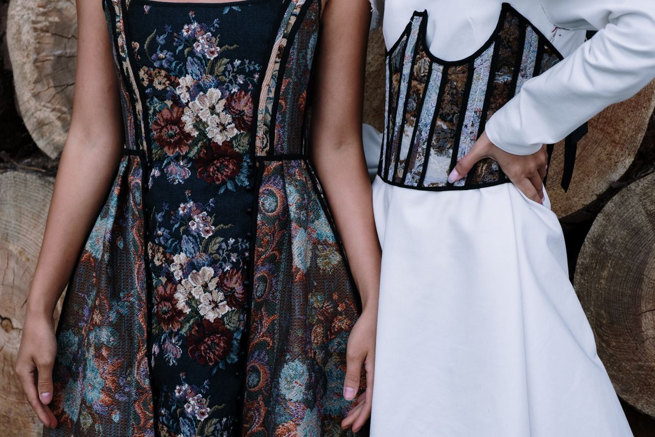 Close-up of two stylish floral dresses with intricate designs and patterns outdoors.