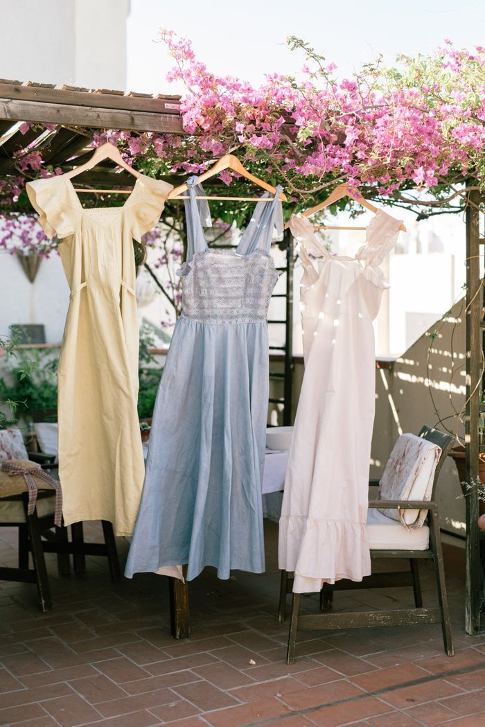 Elegant summer dresses hanging on a patio surrounded by pink flowers, perfect for fashion themes.